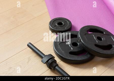 Fitness tools dumbbells yoga mat and shoes on a wooden floor in natural light. Healthy living concept. Stock Photo