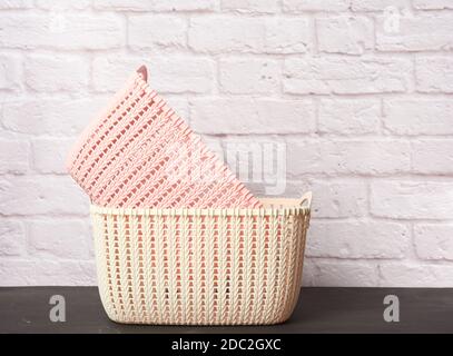 empty white and pink wicker laundry baskets on white brick wall background, close up Stock Photo