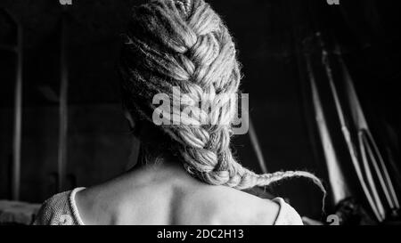 The dreadlocks are braided. The girl's back, hair is visible. Black and white photo Stock Photo