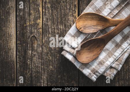 Two wooden spoons on checkered napkin on old wooden table. Top view. Stock Photo