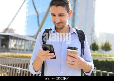 Confident young businessman using cell phone and drinking coffee in the city Stock Photo