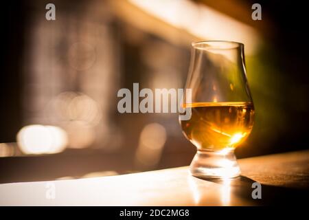 Color close up shot a Glencairn whisky glass on a wooden table, with shallow depth of field. Stock Photo