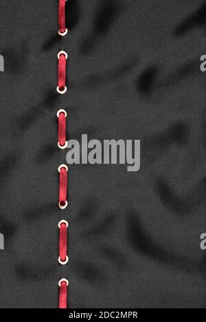 Red satin ribbon inserted in the gold rings on black silk, trendy background Stock Photo
