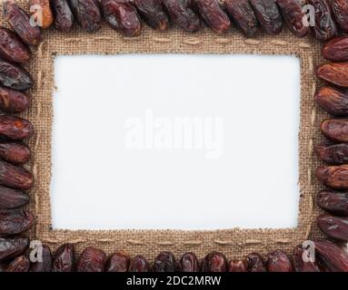 Frame made of burlap with dried dates, on a white background Stock Photo