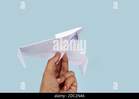 Paper plane on blue background holding in male hand. Stock Photo