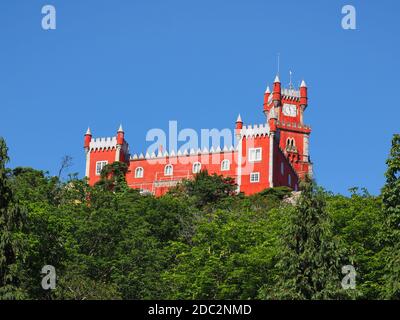 Pena Palace or Palácio da Pena on the top of a hill in the blue sky background. Romanticist castle in the Sintra Mountains, in the Portuguese Riviera. Stock Photo