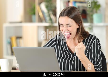 Excited woman checking good news on laptop at home Stock Photo