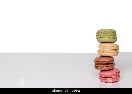 Pastries, desserts and sweets. Close-up on a heap of four colorful macaron cookies on bright table isolated on a white background. Template for your f Stock Photo