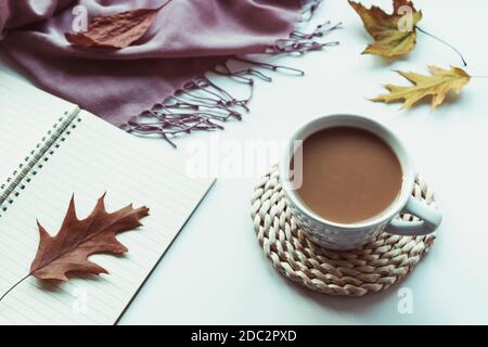 Autumn flat lay with coffee cup, notepad, fallen leaves and pink shawl on white background. Top view, flat lay, copy space. Stock Photo