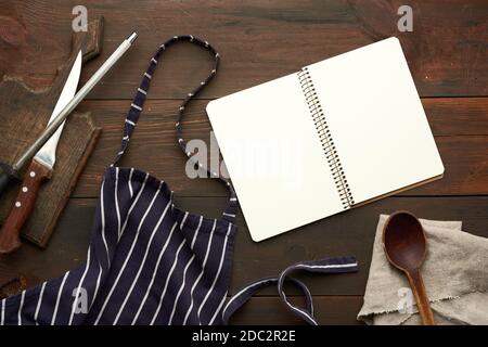 open notebook with blank white sheets and kitchen utensils on brown wooden table, top view Stock Photo