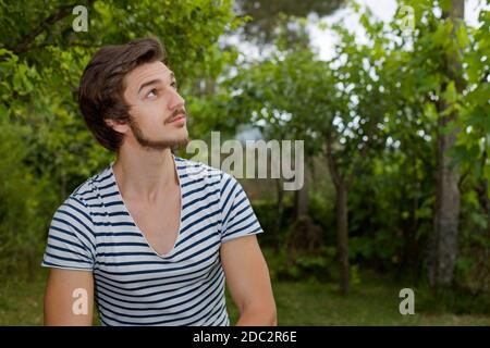 young casual man seated, smiling, outdoors Stock Photo