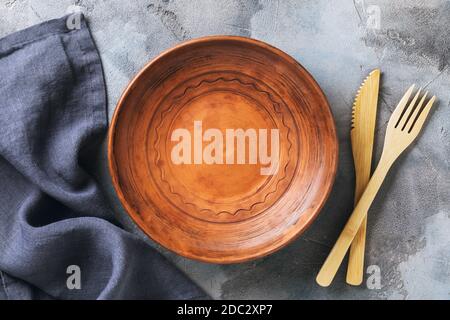 Empty clay plate, cutlery and napkin on the table, top view. Food background Stock Photo