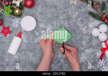 Christmas crafts - Christmas tree made of colored paper, step by step instructions. Step 19- cut off excess paper from the bottom Stock Photo