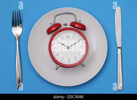 There is a red alarm clock on white plate Stock Photo
