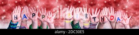 Children Hands Building Colorful English Word Happy Birthday. Red Snowy Christmas Winter Background With Snowflakes And Sparkling Lights Stock Photo