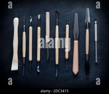 flat-lay  selection of pottery tools for clay on a deep slate background  shot from above close up ideal for text over Stock Photo