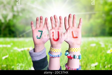Children Hands Building Colorful Swedish Word Jul Means Christmas. Sunny Green Grass Meadow As Background Stock Photo