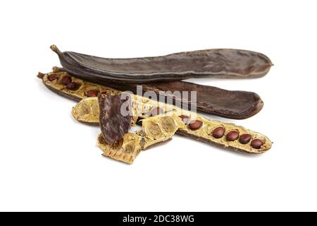 Carob pods with seeds isolated on white background. Healthy organic sweet carob fruit. Stock Photo