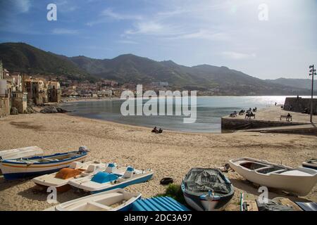 Céfalu, Sicily, Italy - March 16, 2018: a relaxing sunny day at the beach of Céfalu, with few unrecognisable people and old typical buildings Stock Photo