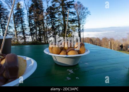 Eating fritter balls covered in hot, melted chocolate at the peak of mountain Medvednica above Zagreb city, Croatia, observing fog covered town beneat Stock Photo