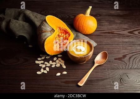 Homemade pumpkin soup with cream and pumpkin seeds on wooden table. Autumn thanksgiving day food concept. Stock Photo