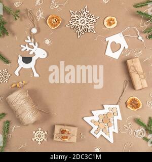 XMAS or New Year composition. Frame, border made from boxes, twine, wood decoration, dried oranges and spruce branches on craft beige background. Conc Stock Photo