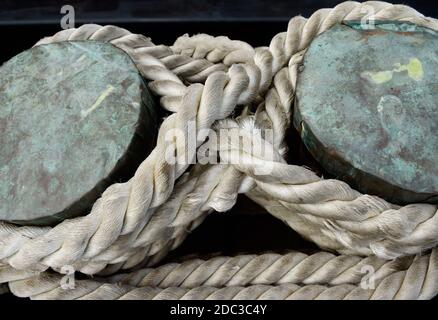 Close-up view at ancient mooring bollard with sturdy ropes. Stock Photo