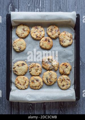 Shortbread with dates on a baking sheet is laid out on a dark wooden surface. Top view. Stock Photo