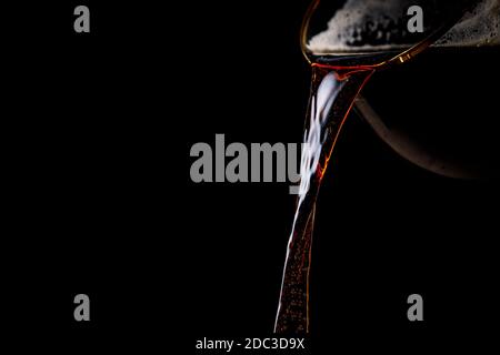 Dark beer is pouring from the glass Stock Photo