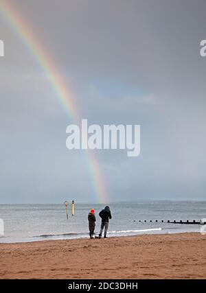 Portobello, Edinburgh, Scotland, UK. 18 November 2020. Rainbow at the seaside,10 degrees but windchill makes it feel cooler for this couple walking on the shoreline of the Firth of Forth. Credit: Arch White/Alamy Live News. Stock Photo