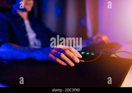 A professional gamer plays online video games in the first person on his personal computer, sitting in a room with neon lights. Online cyber sport cha Stock Photo