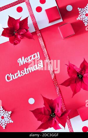 Text Merry Christmas. Poinsettia, snowflakes, pink white paper confetti. Top view, monochrome design Stock Photo