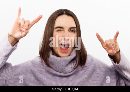 Young beautiful girl wearing casual purple sweater standing over isolated white background shouting with crazy expression doing rock  Stock Photo