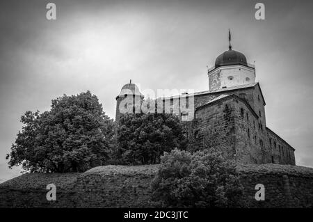 Vyborg castle on the hill amid clusters of trees. Black and white Stock Photo