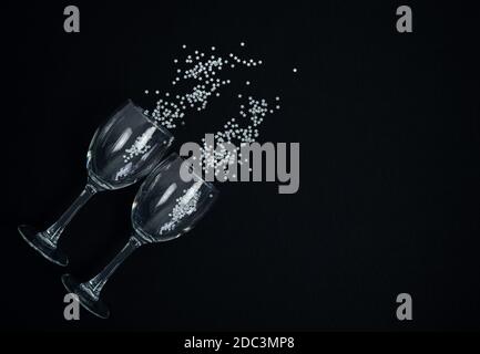 Wine glasses with silver confetti on a black background. Copy space. Stock Photo