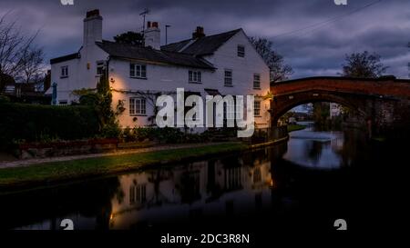 Bridgewater canal Lymm Moody clouds from day to dusk lights on the outside building Stock Photo