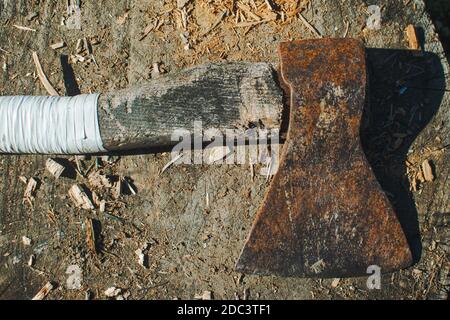 A vintage ax with a white handle laying on the stump Stock Photo