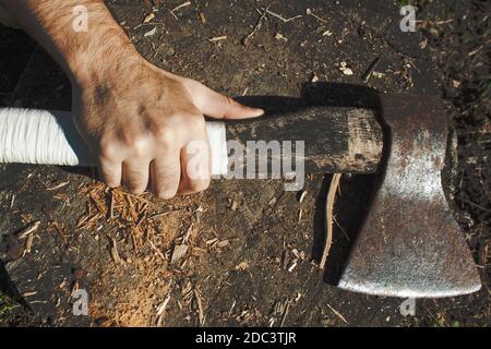 A European man hand tightens a white handle of an old ax on the stamp background Stock Photo