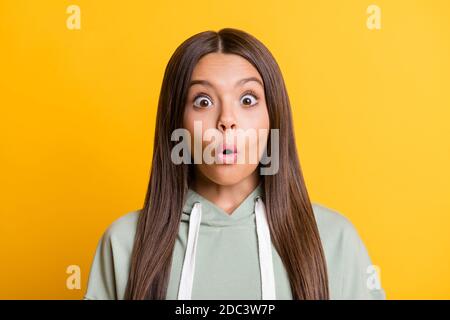 Photo of cute shocked child girl dressed casual green outfit big eyes lips pouted isolated yellow color background Stock Photo