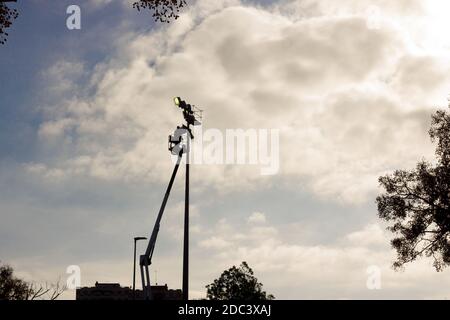 Electrician repairing a light tower in a sports hall. The electrician must be trained because it is a risky job. Professional installing the lighting Stock Photo
