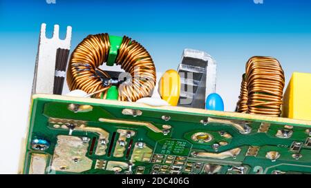 Toroidal electronic inductors soldered on circuit board. Copper wire winding on induction coils. Electric components and aluminum cooler. Bottom view. Stock Photo