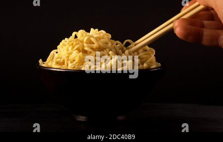 Hand uses chopsticks to pick up chinese noodles. Stock Photo