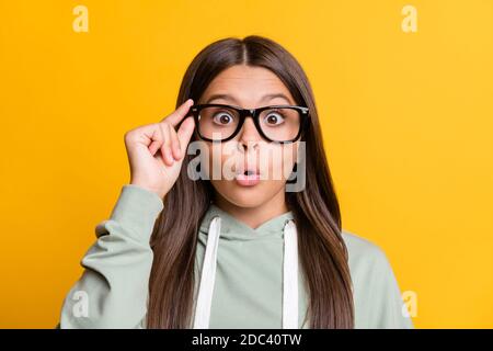 Photo of shocked funny child girl dressed casual green outfit arm eyewear lips pouted isolated yellow color background Stock Photo