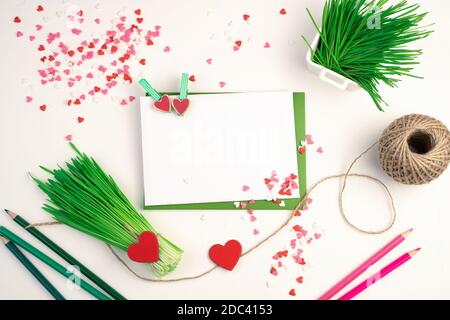 A bouquet of green wheat sprouts, envelopes, pencils and hearts on a light background. Stock Photo