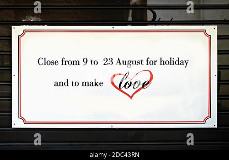 Closed for holiday and to make love, written on a sign on a closed shutter of a store. Summer season holidays.