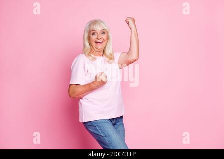 Photo portrait of laughing grandmother gesturing like winner smiling wearing casual outfit isolated on pastel pink color background Stock Photo