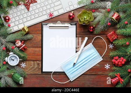 Christmas background with fir branches, keyboard, clipboard on old wooden board  Stock Photo