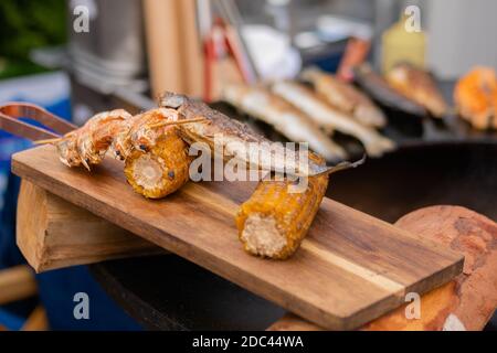 Grilled shrimp, prawn skewer and corn cobs on wooden cutting board Stock Photo