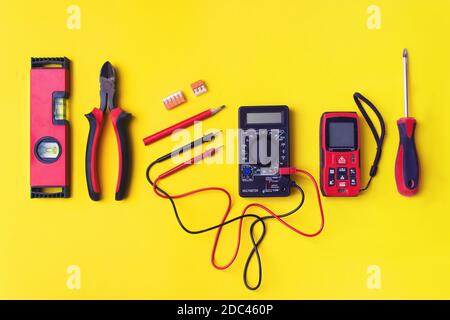 Different electrician's supplies on yellow background. Background of professional electrician tools with space for text Stock Photo