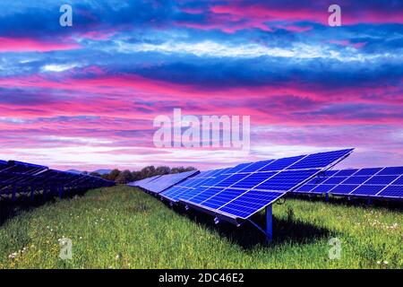 Solar panel on purple sunset sky background. Green grass and cloudy sky. Alternative energy concept Stock Photo